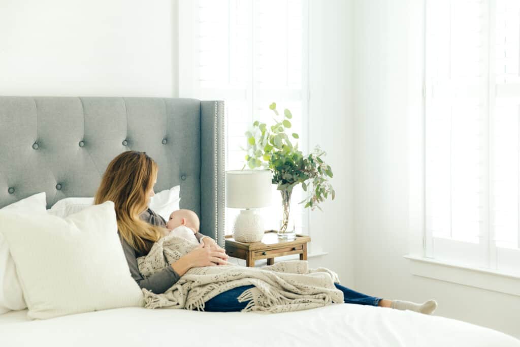Woman breastfeeding a baby on a bed.