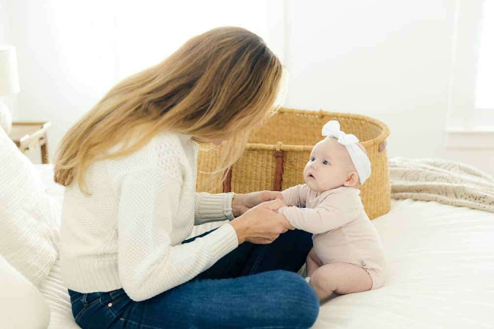 Woman sitting on her bed with a baby