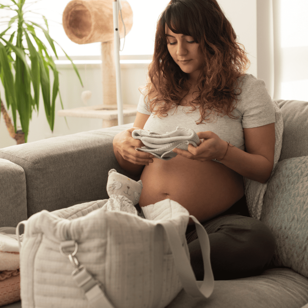 Pregnant woman folding and packing baby clothes.