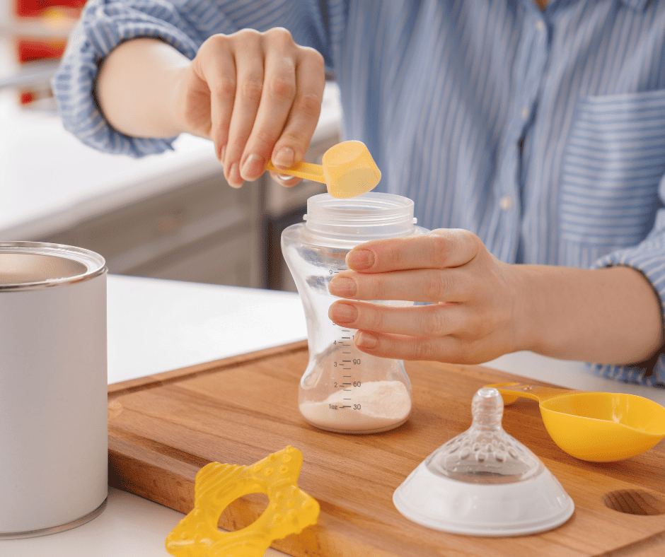 Person scooping out formula into a baby bottle