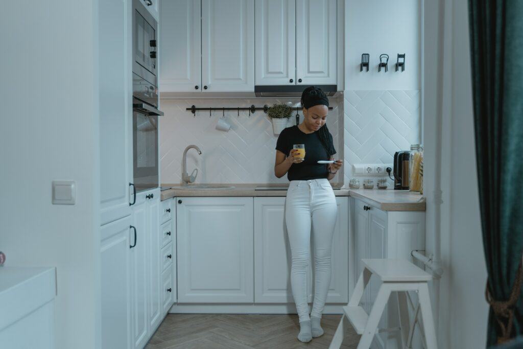 First trimester survival guide Woman in kitchen drinking juice and looking at pregnancy test