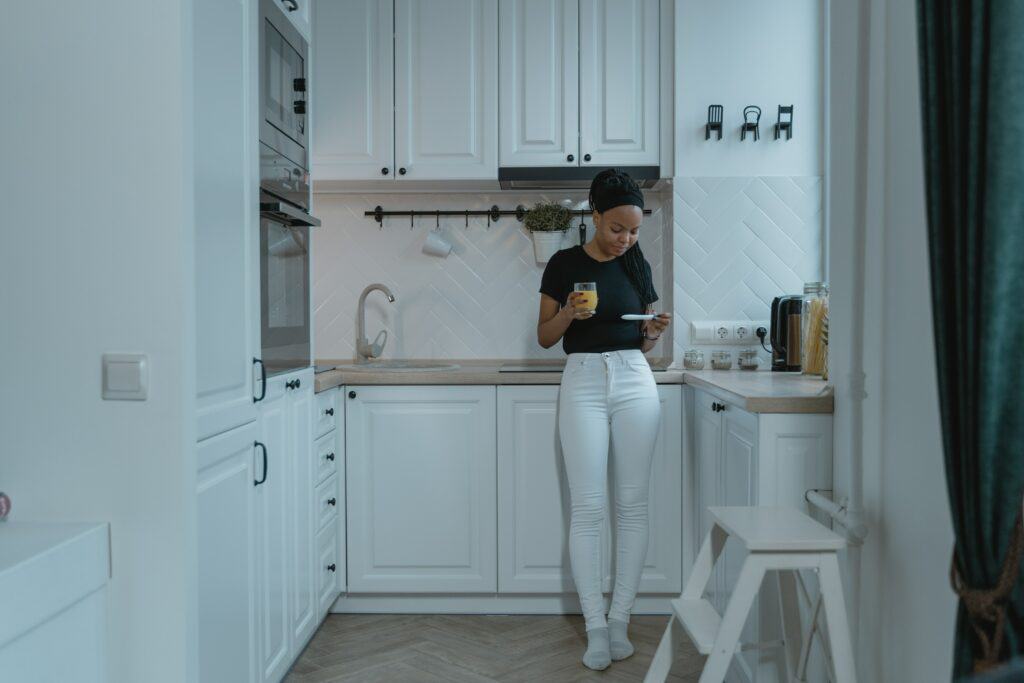 Woman in kitchen drinking juice and looking at pregnancy test