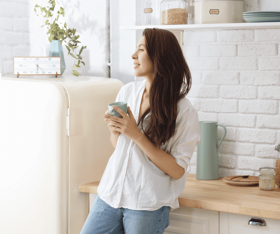 Woman in kitchen drinking coffee