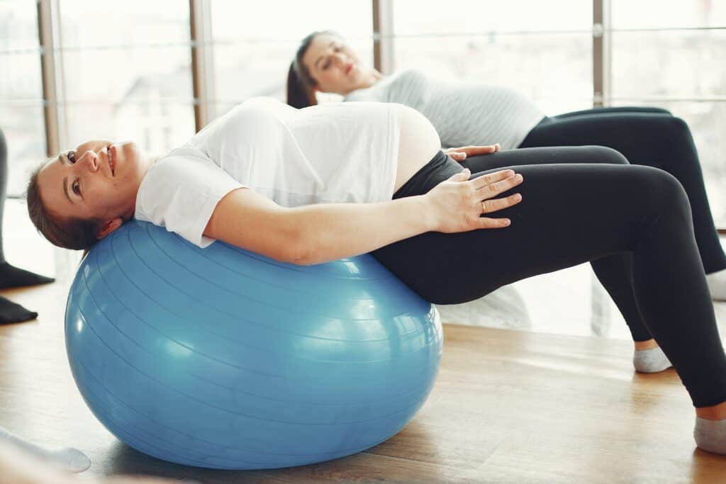 Two pregnant woman leaning back on exercise balls