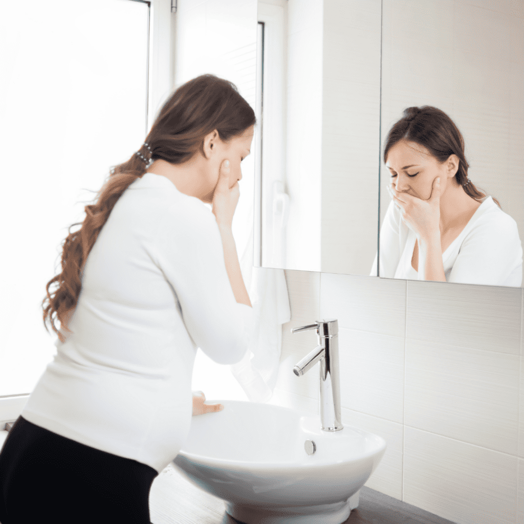 Woman standing in front of basin holding mouth