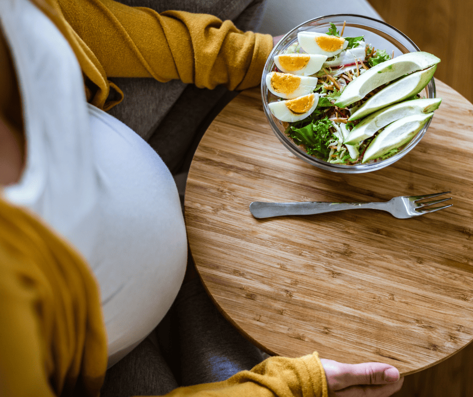 Pregnant woman eating a salad with avocado and eggs