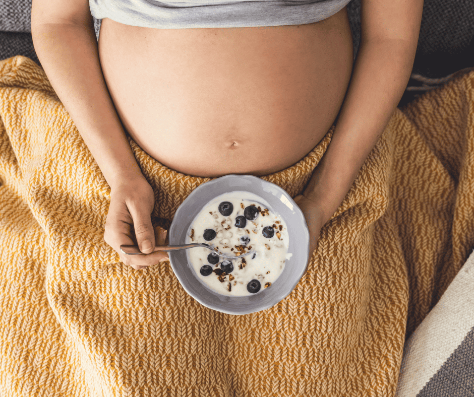 Pregnant woman eating a bowl of cereal with blueberries