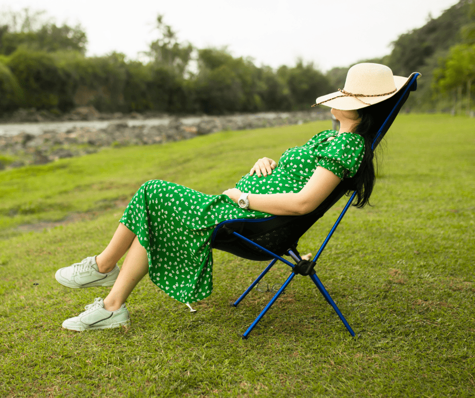 Healthy pregnancy habits Pregnant woman sitting outside with hat covering her face