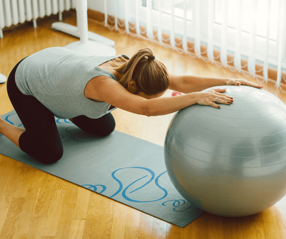 Pregnant woman stretching back on shoulders with exercise ball