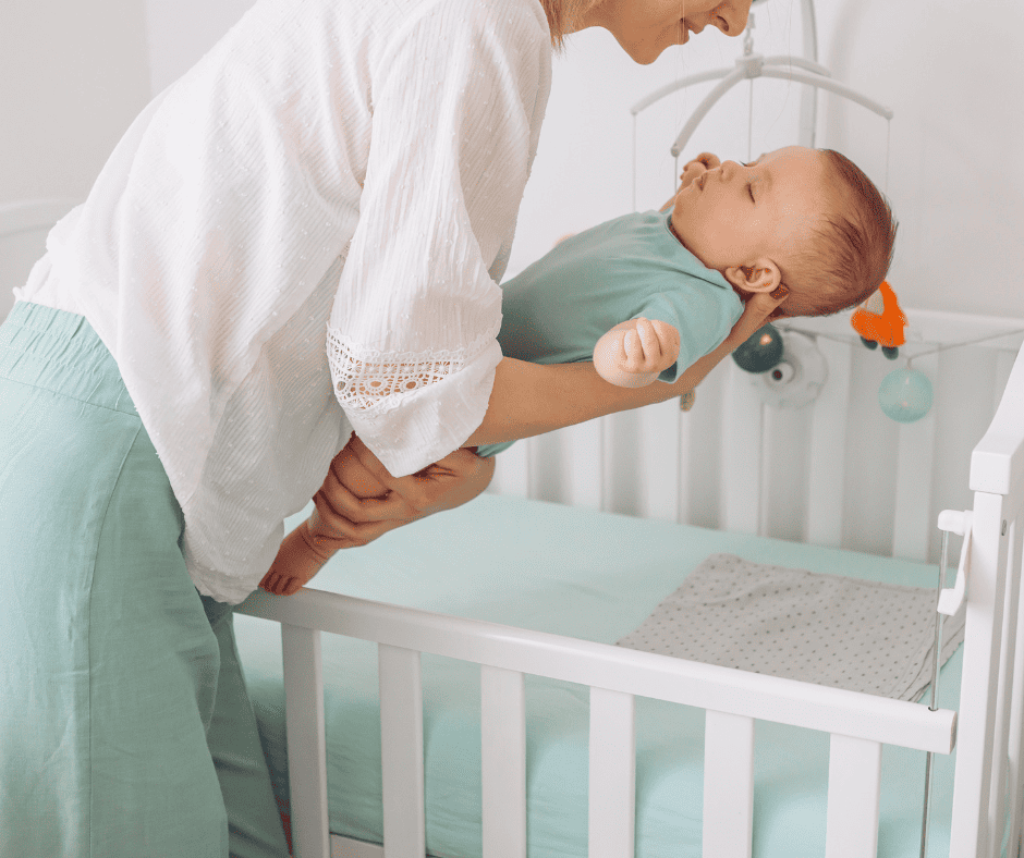 Woman putting sleeping baby in crib