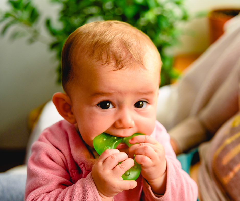 Baby chewing on green teething ring